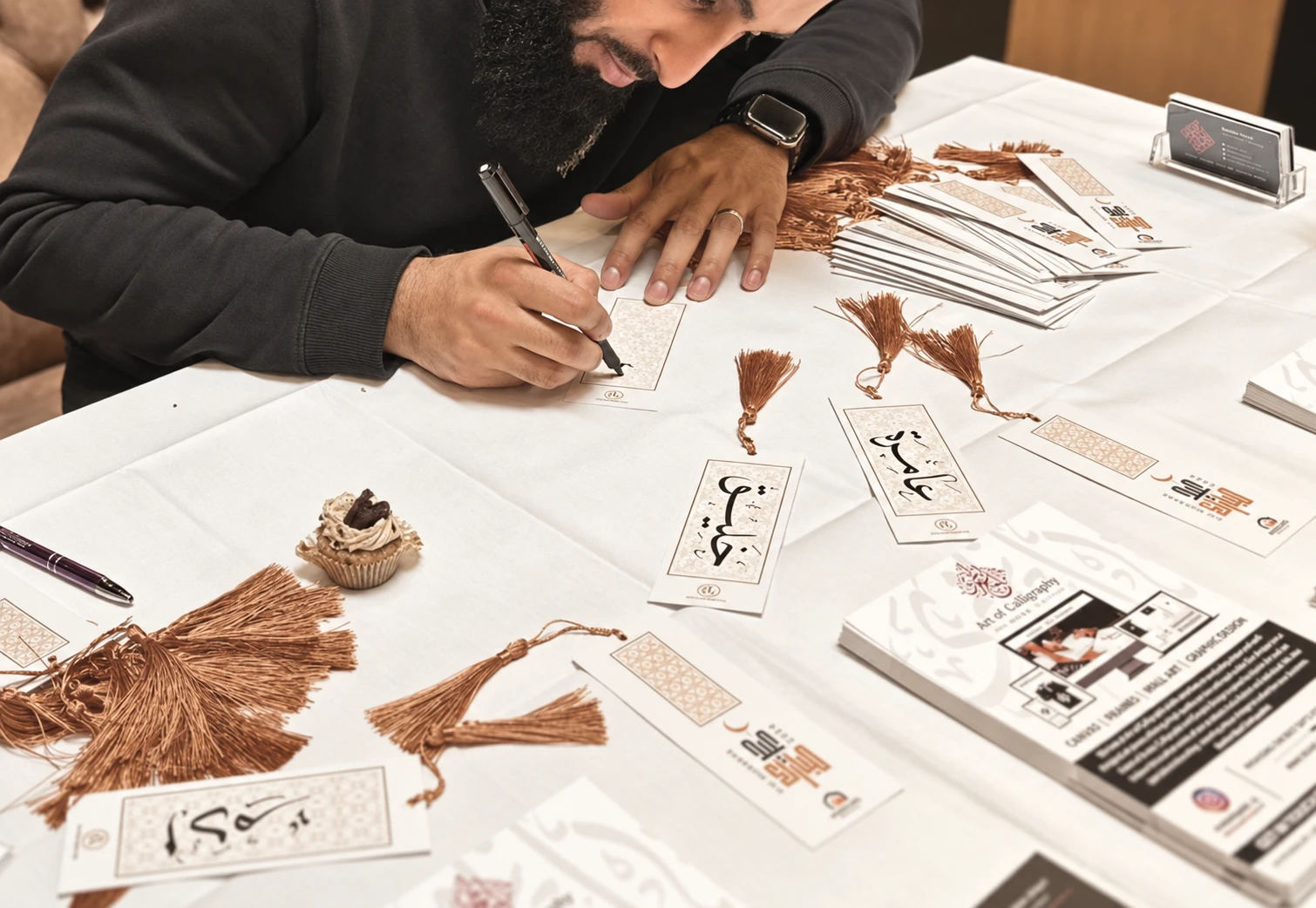 An artist hand-lettering Arabic calligraphy bookmarks